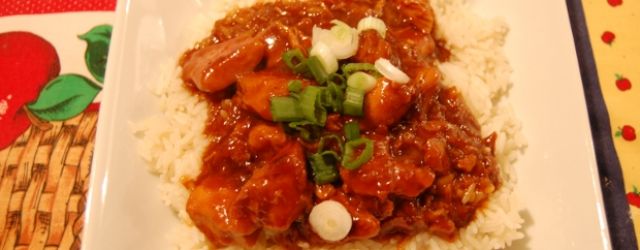 Orange Chicken with Rice garnished with citrus, served on a white plate